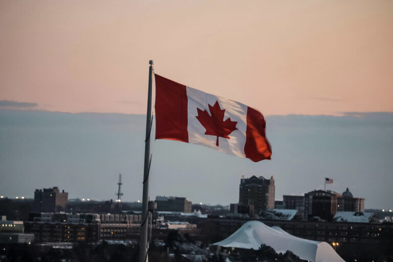 Canadian flag over city skyline at sunset Canada immigration