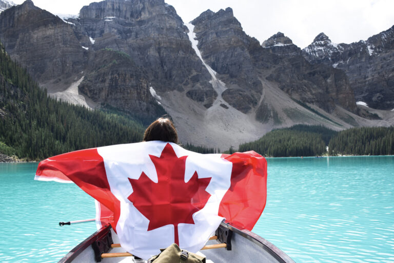 Newcomer with Canadian flag in canoe at mountain lake