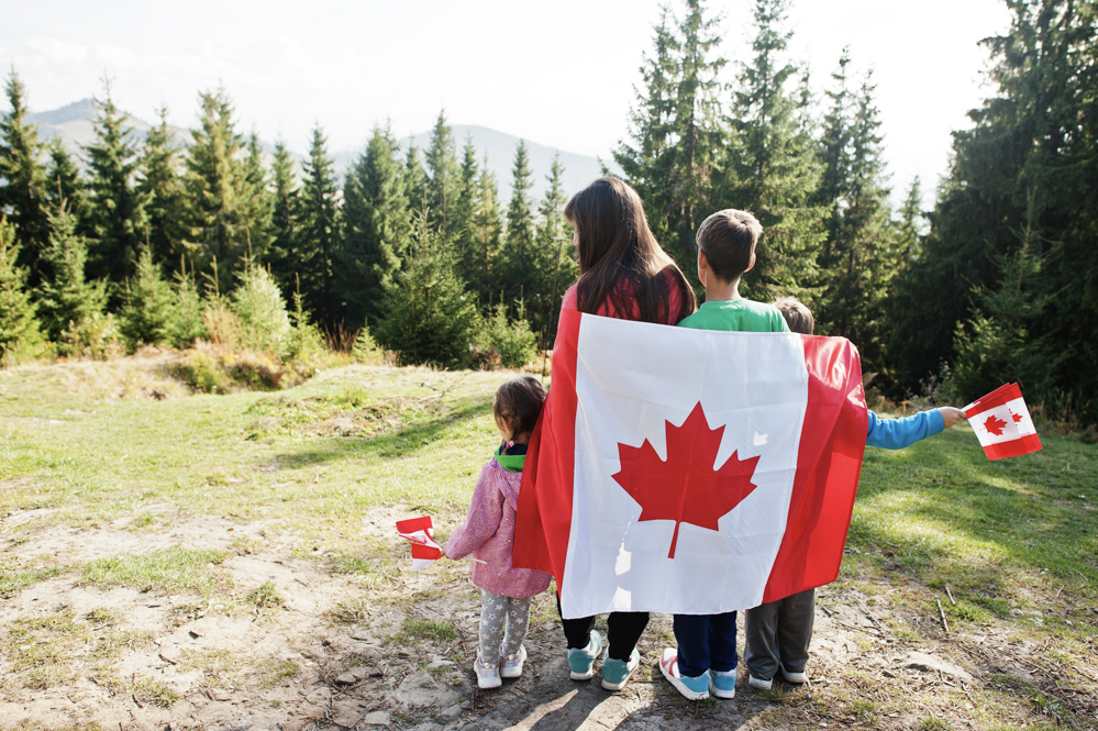 Newcomer holding Canadian flags proudly