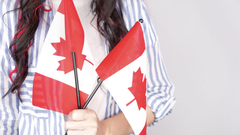 Newcomer holding Canadian flags proudly