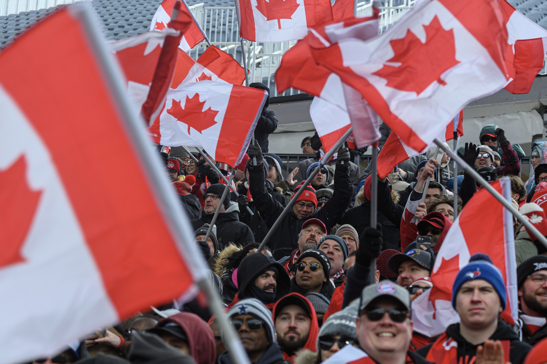 Crowd waving Canadian flags at public event