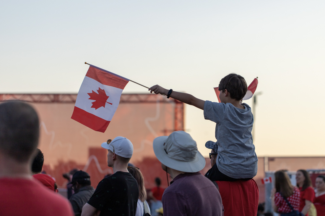 Child waving Canadian flag at newcomer event